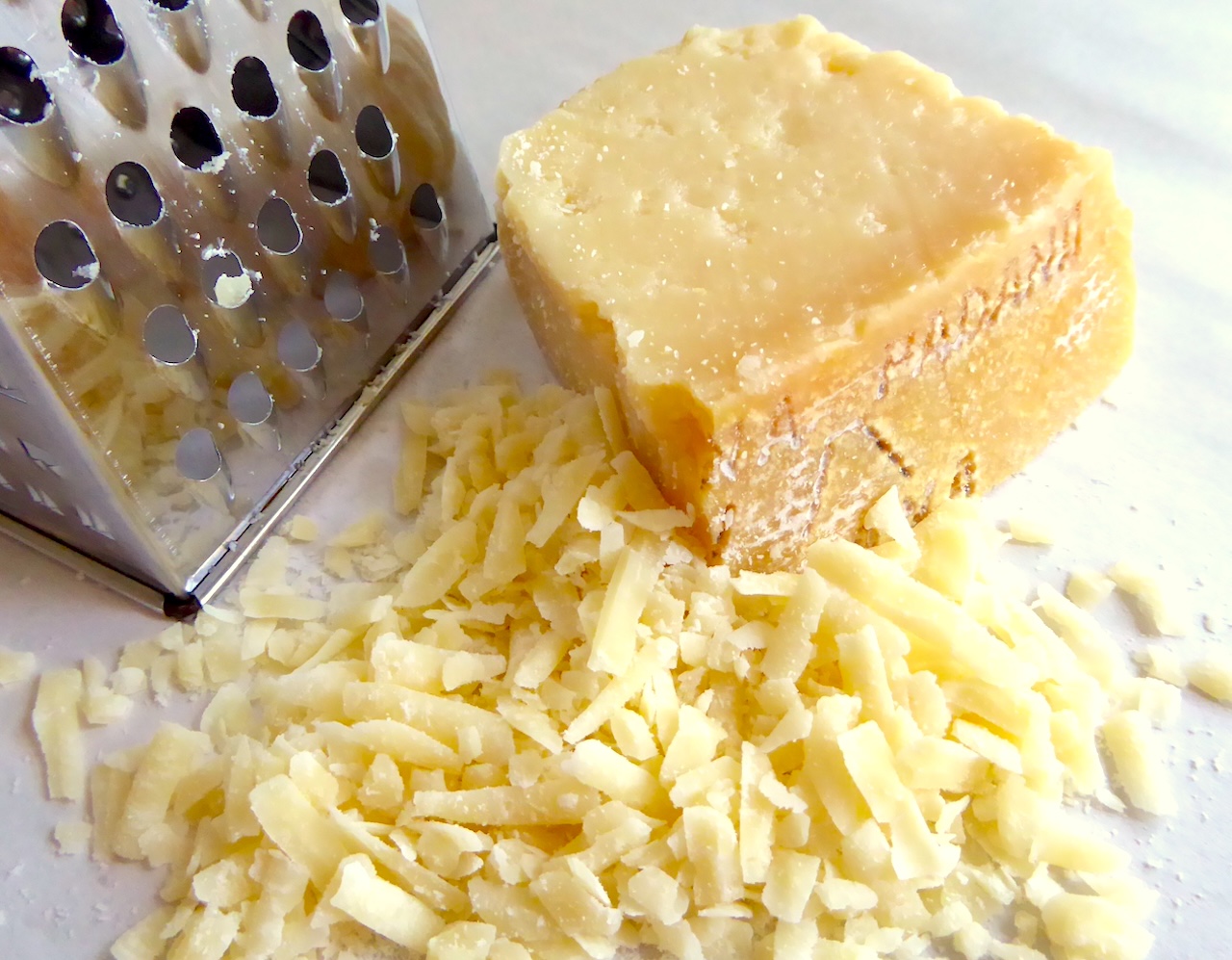 Cheese grater and pile of grated cheese